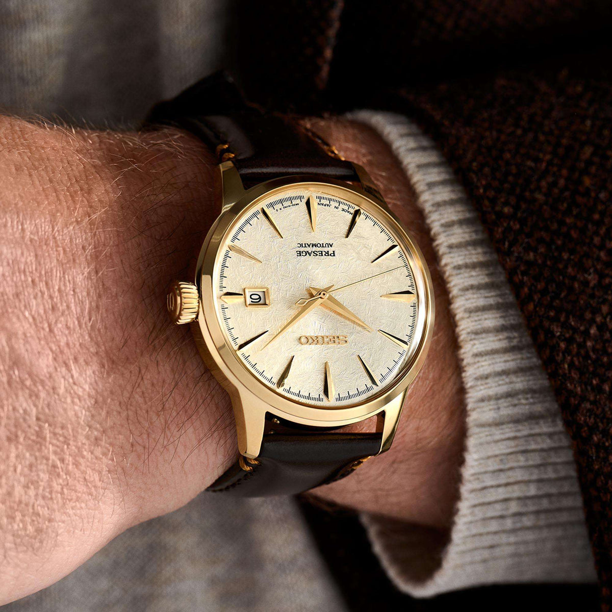 Seiko Presage gold wristwatch SRPH78J1 with a brown strap on a person's wrist, close-up shot.