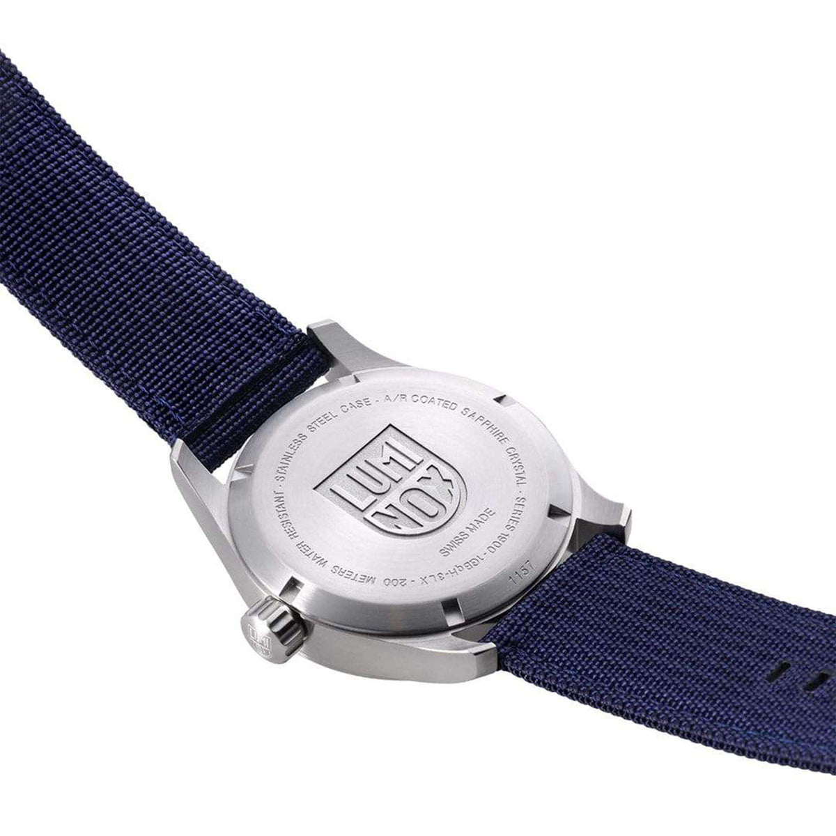 Watch case back with LUMINOX logo on blue woven fabric strap; metal crown hardware