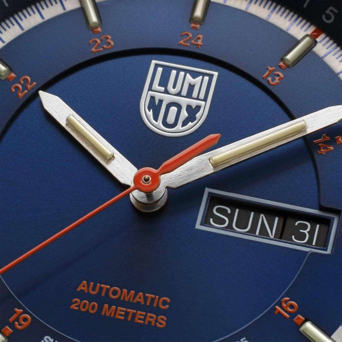 Blue dial close-up with LUMINOX shield, orange hands, and SUN 31 date window
