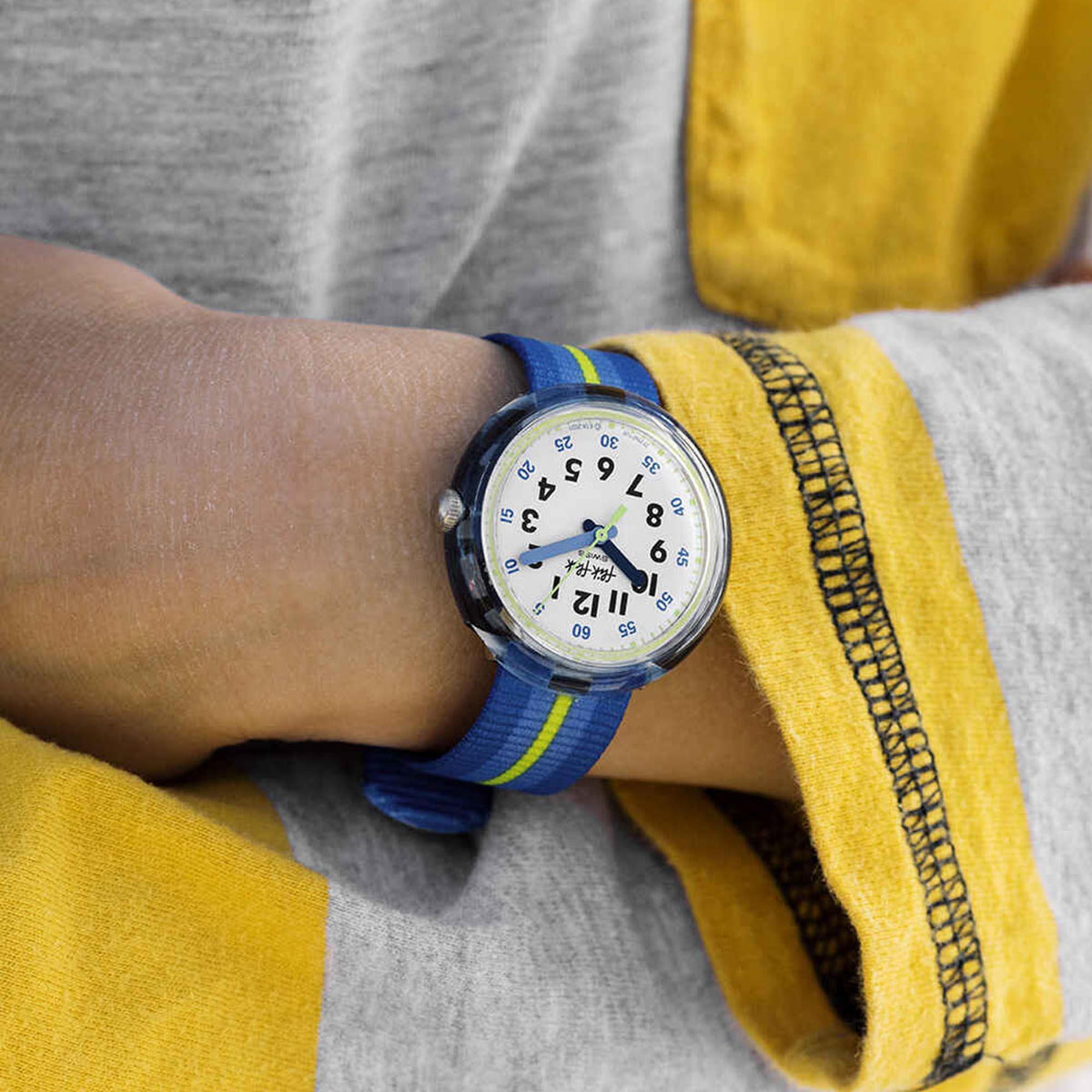 Boys' wristwatch on wrist with blue dial and blue fabric strap with green stripe
