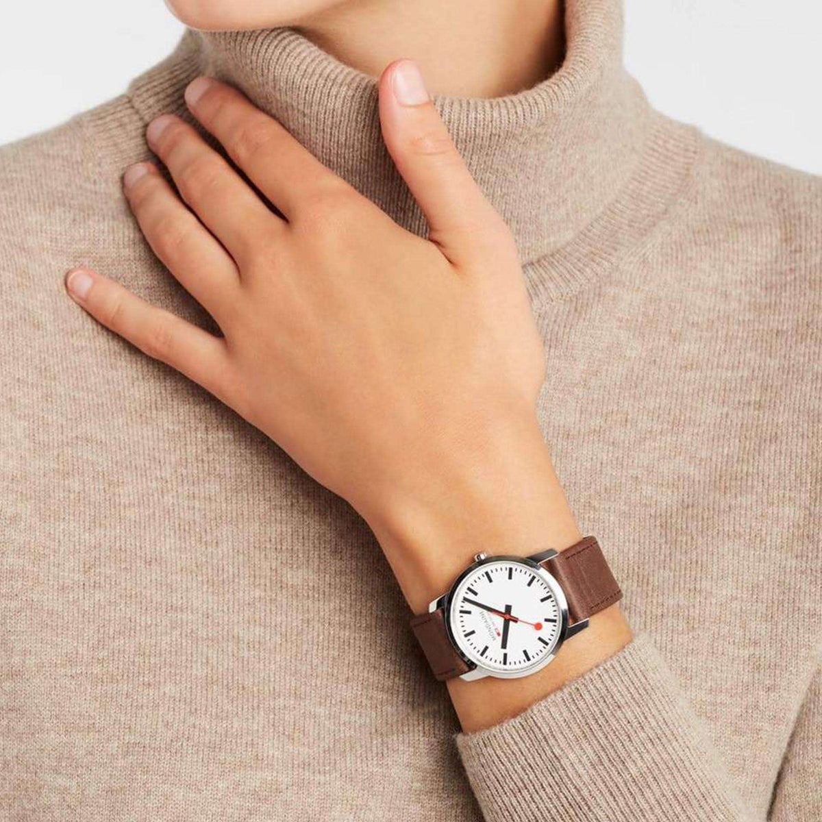 Mondaine quartz wrist watch worn on wrist, white dial, red hands, brown leather strap