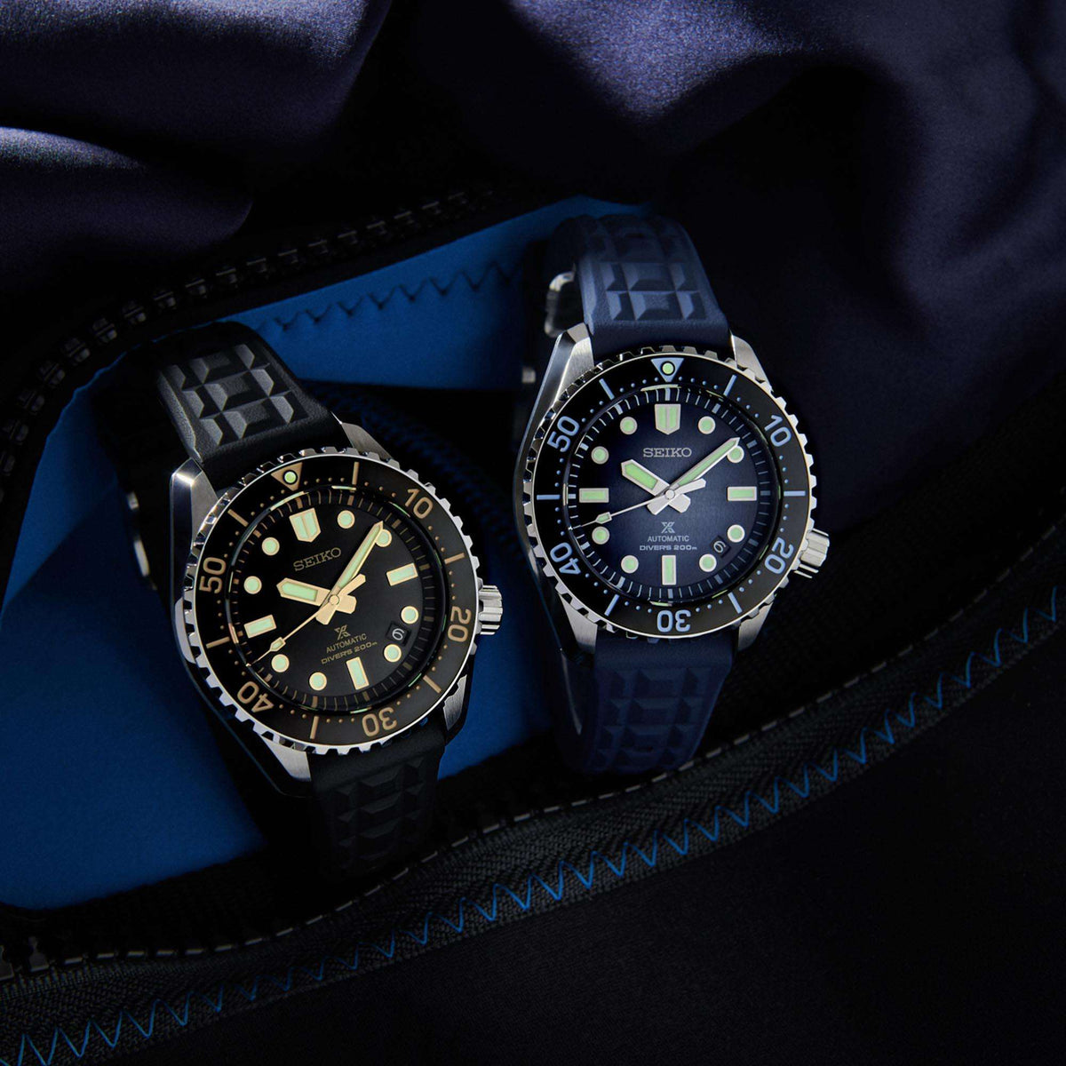 Two men's Seiko dive watches with dark blue dials and black rubber straps