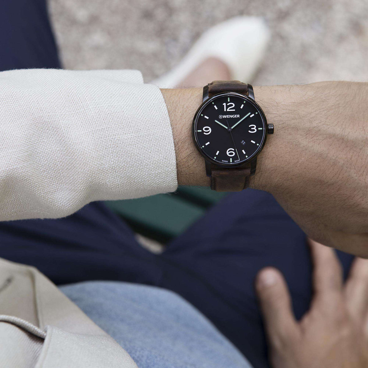 Men’s watch on wrist with black dial, silver bezel, and brown leather strap
