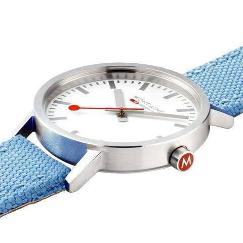 Mondaine quartz wristwatch close-up with blue woven strap, silver bezel, white dial, crown