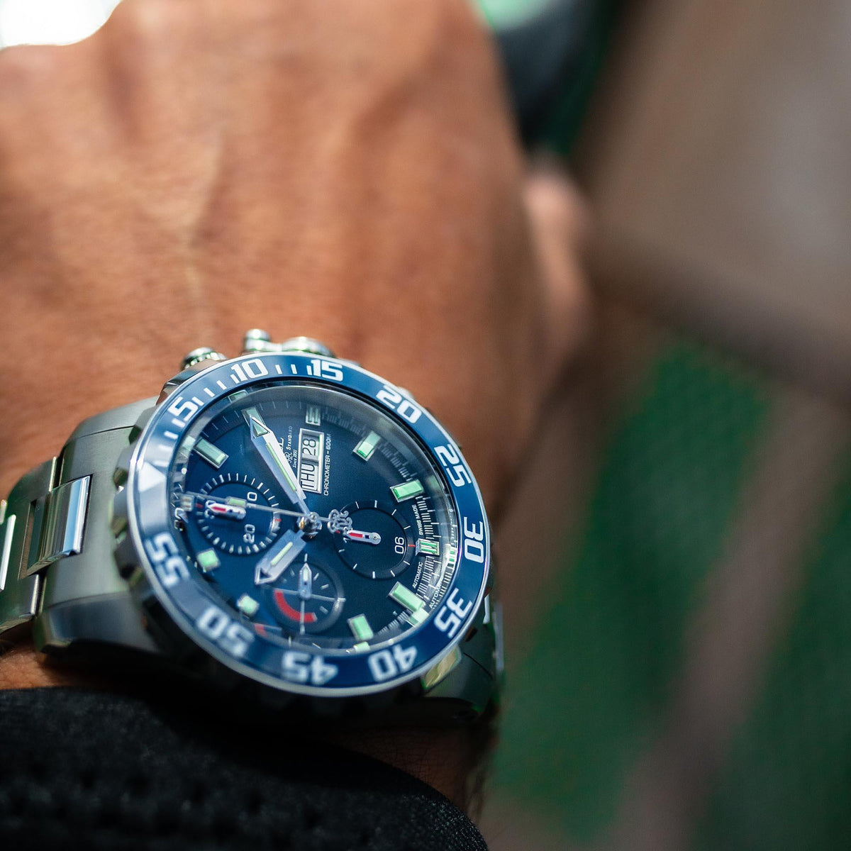 Men's steel automatic watch close-up with blue dial and luminous hour markers