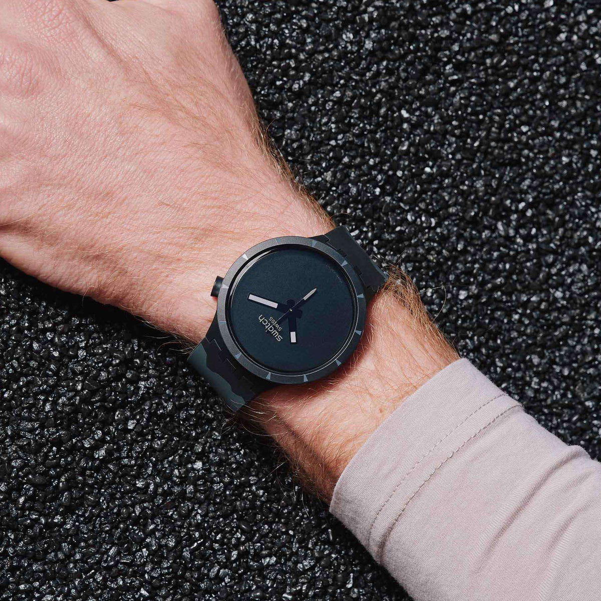 Black dial watch on wrist with silicone strap and rectangular hour markers