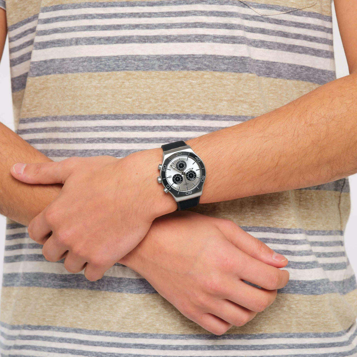 Men's quartz watch on wrist with silver dial and black silicone strap, side view