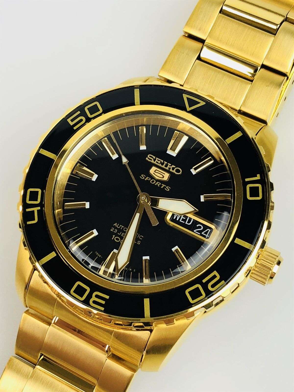 Gold-tone Seiko 5 Sports watch with black dial, rotating bezel, and date display Wed 24
