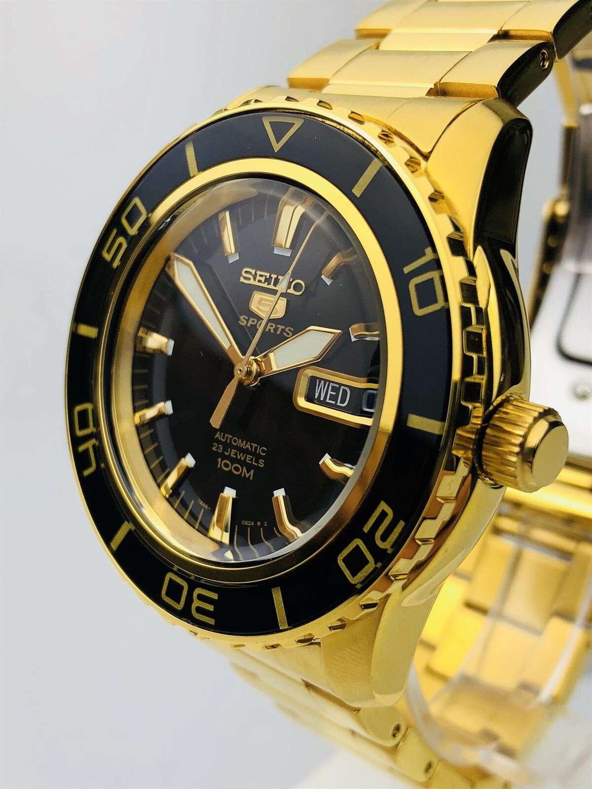 Gold-tone men’s watch with black dial, gold bezel, and Wed 24 date window
