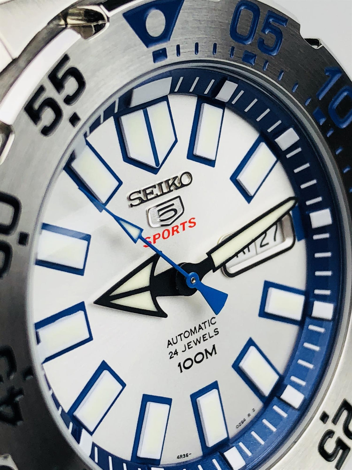 Close-up of men's sports watch dial with blue indices, bold hands, and SEIKO 5 logo
