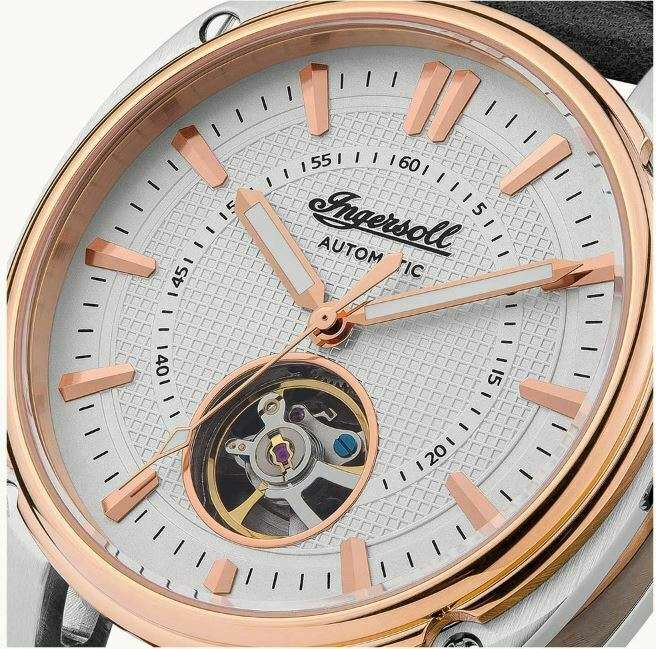 Automatic watch dial close-up with rose-gold hands, hour markers, and open movement