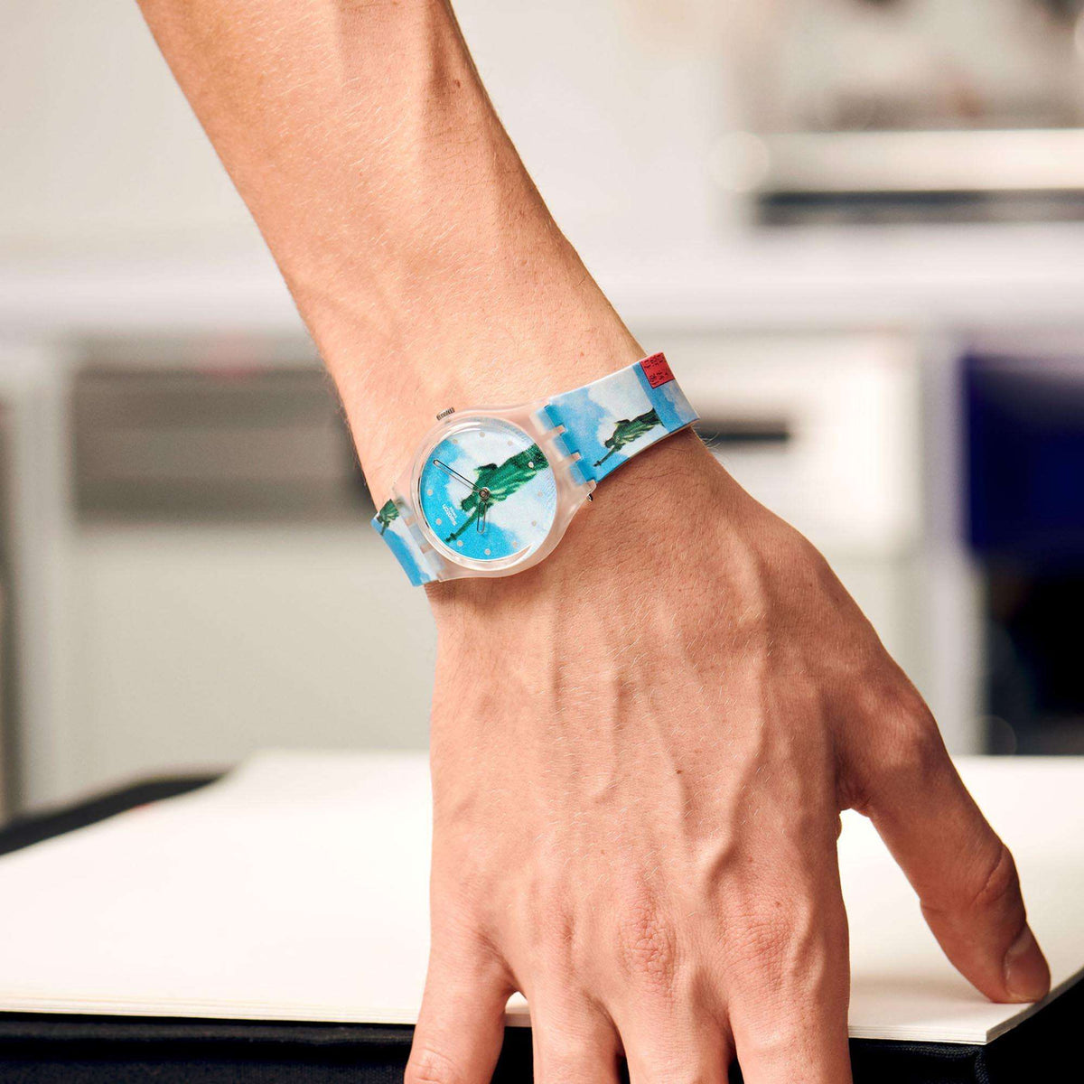 Blue dial Swatch watch with Statue of Liberty print on silicone strap worn on wrist