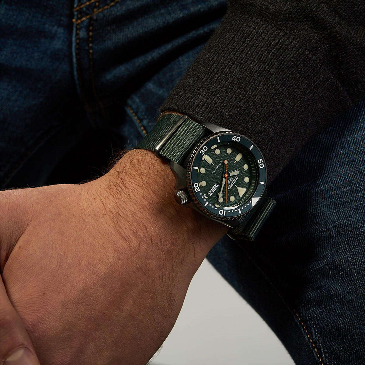 Men's wrist watch with green dial, stainless case, and dark green fabric strap.