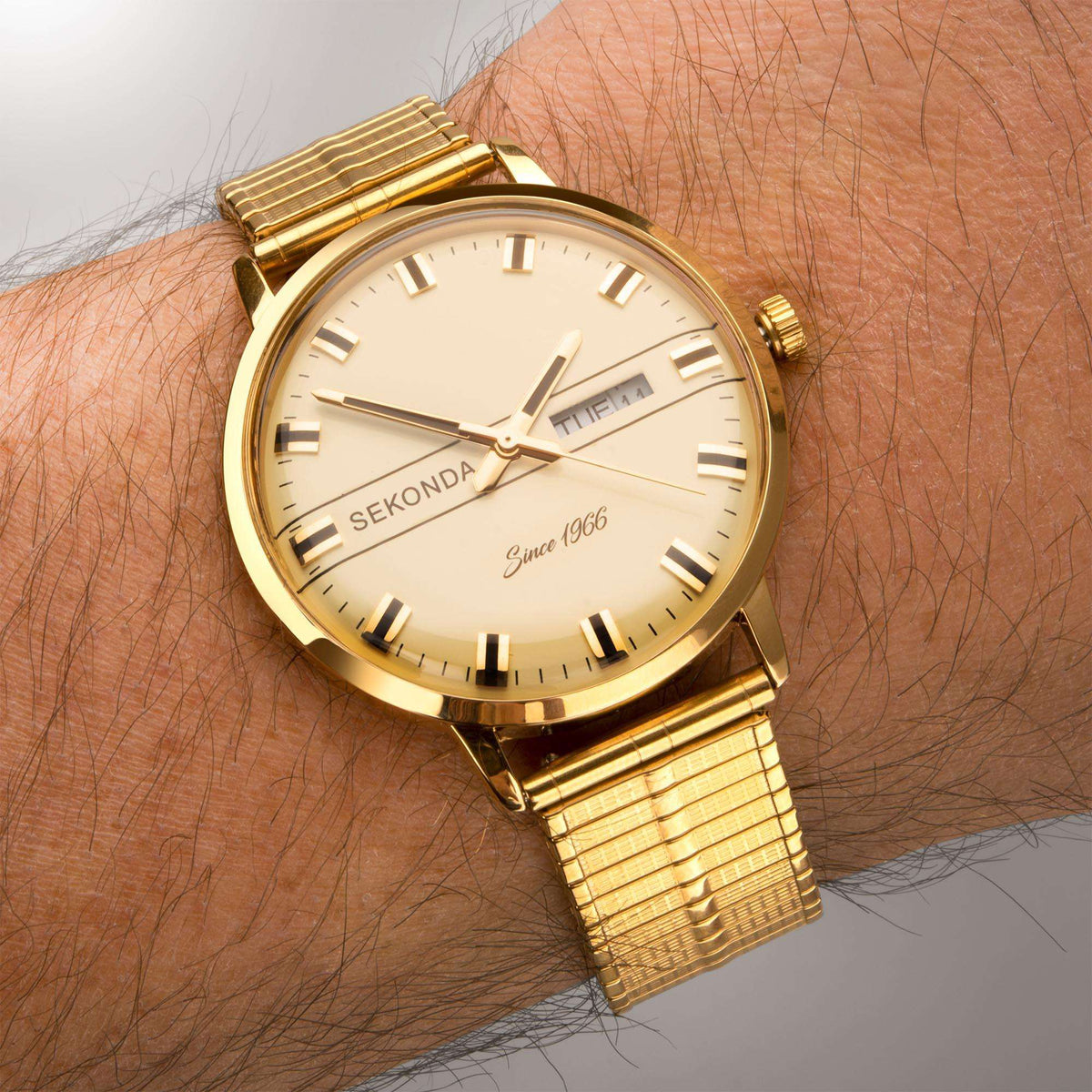 Gold-tone quartz watch on wrist with cream dial and metal bracelet