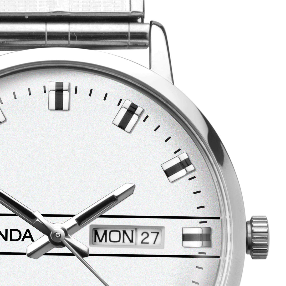 Quartz watch dial close-up with white face, black hands, Mon 27 window, steel case
