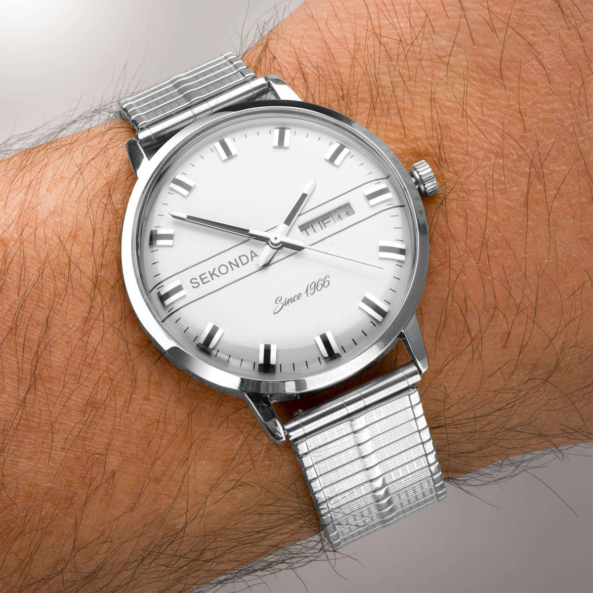 Quartz watch on wrist with white dial, baton markers, Mon 27 date window, steel bracelet