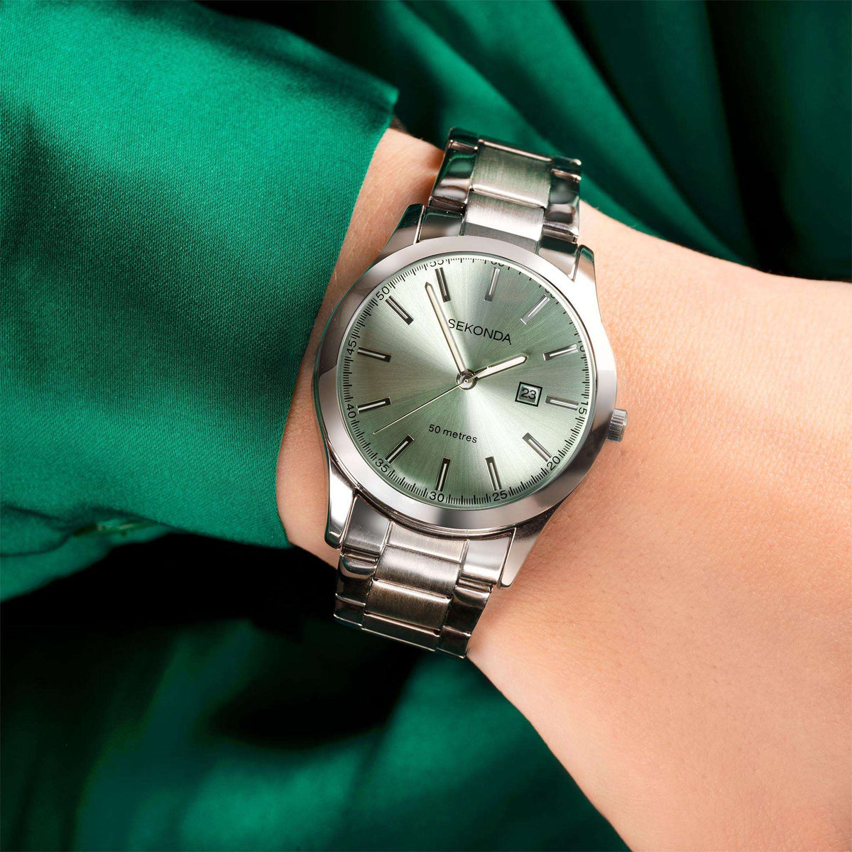Stainless steel ladies watch on wrist with green dial and date window at 24