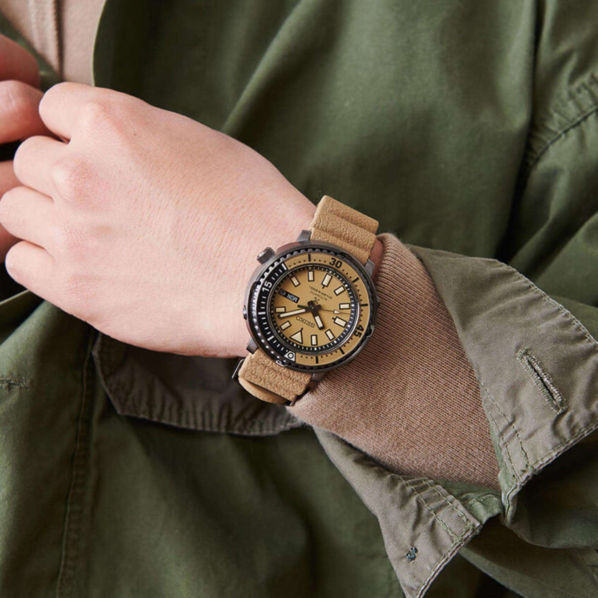 Automatic diver watch on wrist with beige dial, tan leather strap and black bezel