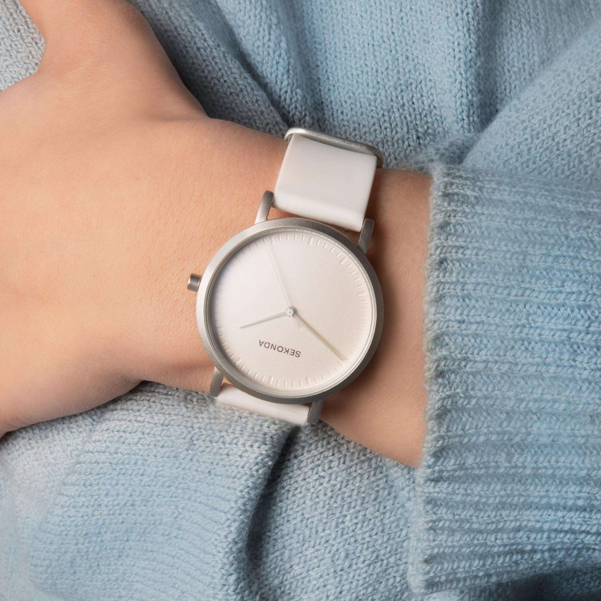 Ladies quartz watch on wrist with white dial, silver-toned case, white silicone band
