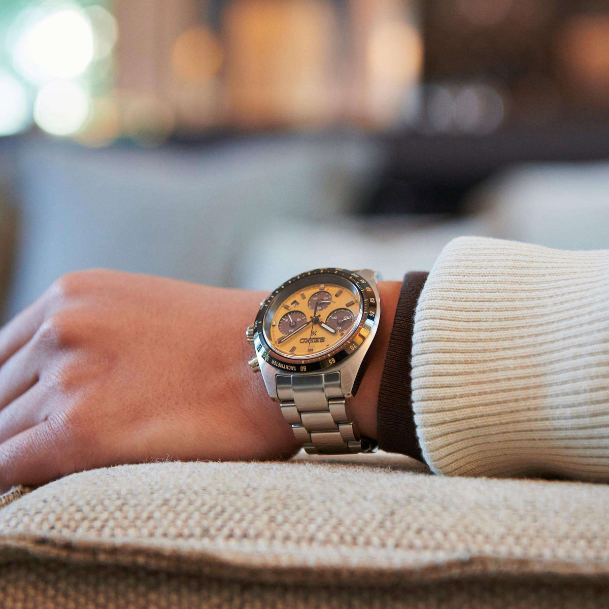 Seiko chronograph watch on wrist with gold dial and steel bracelet, subdials visible