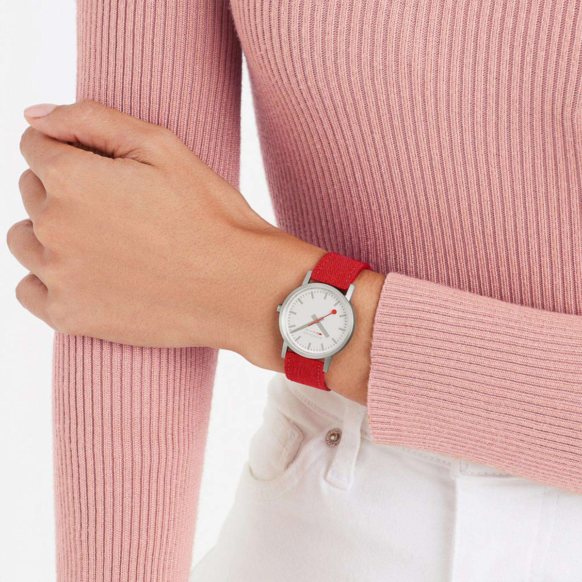 Quartz watch on wrist with white dial and red textile strap, worn with pink knit