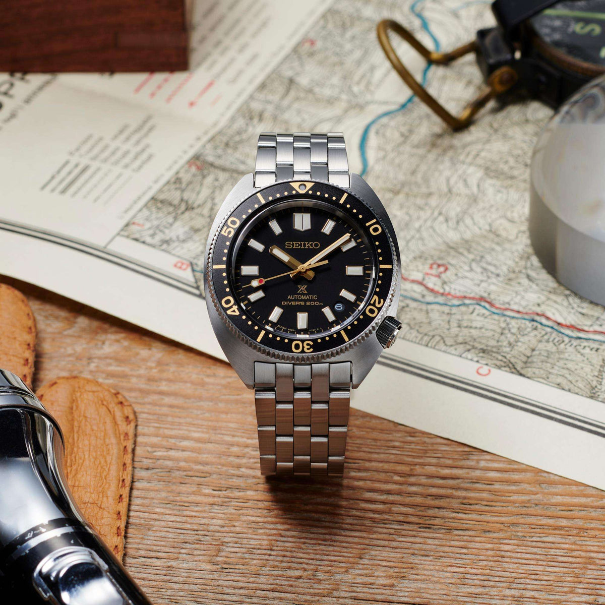 Stainless steel diver watch with black dial and gold indices on linked bracelet