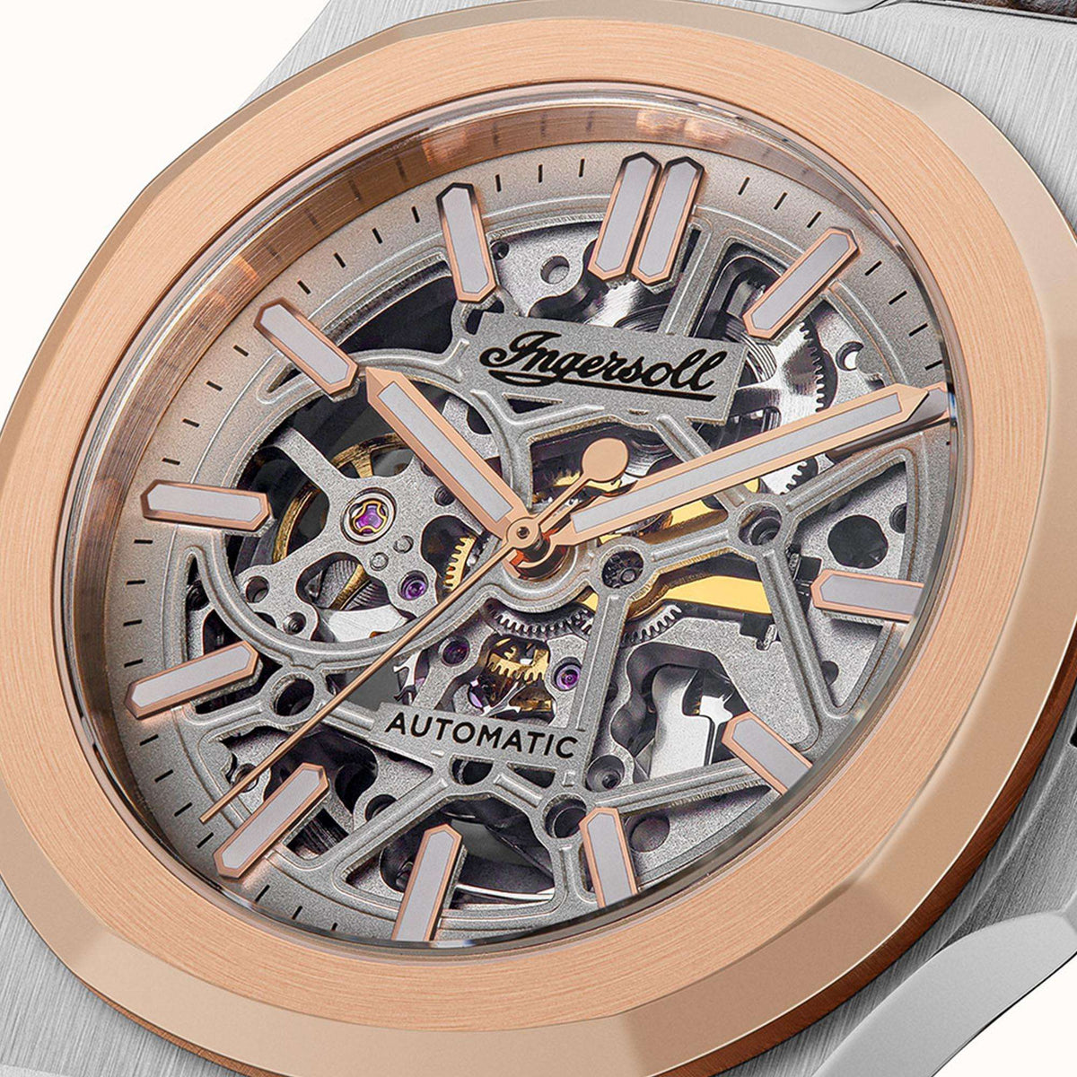 Men's automatic skeleton watch dial close-up with rose-gold bezel over silver case