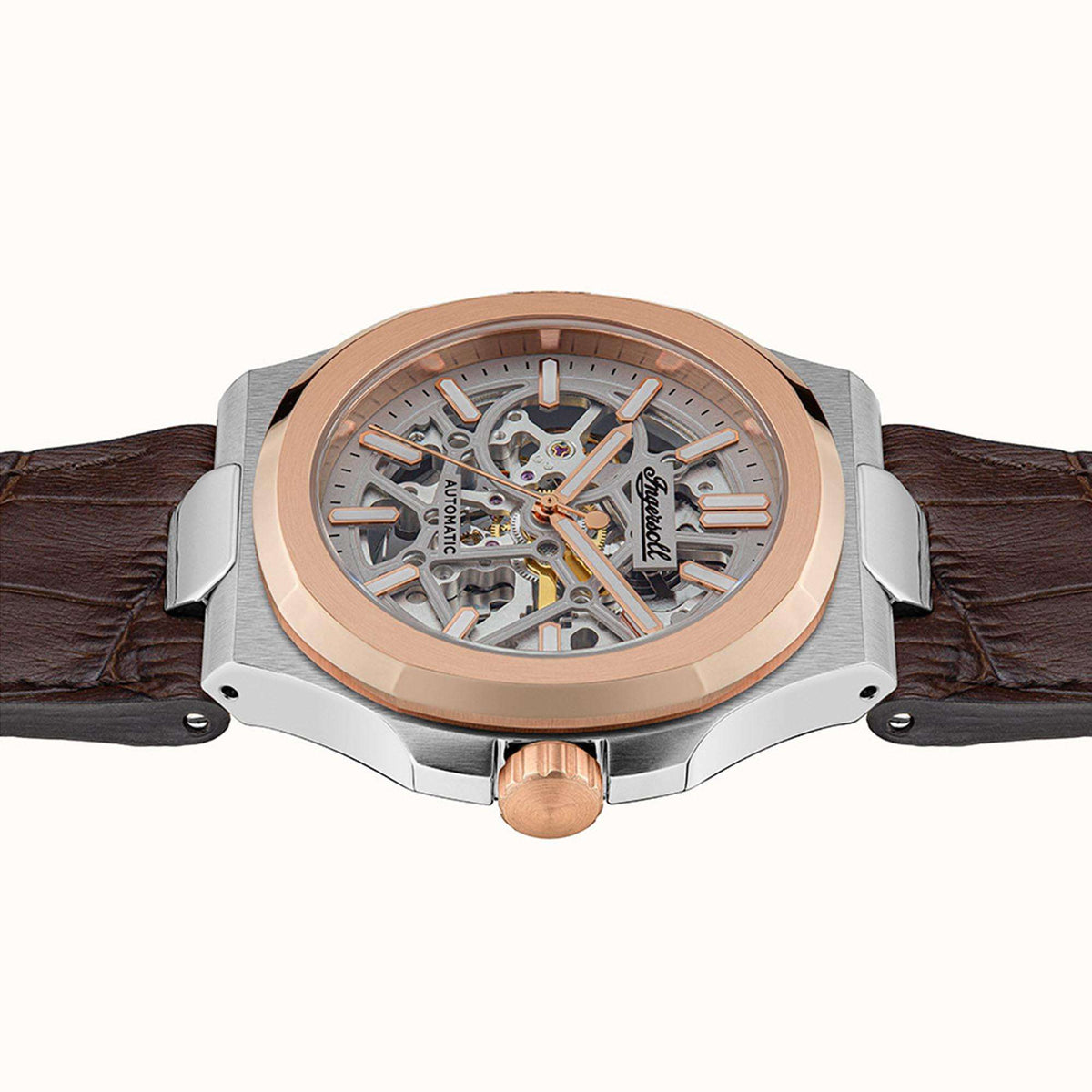 Men's automatic skeleton watch front view with silver case, rose-gold bezel, brown strap