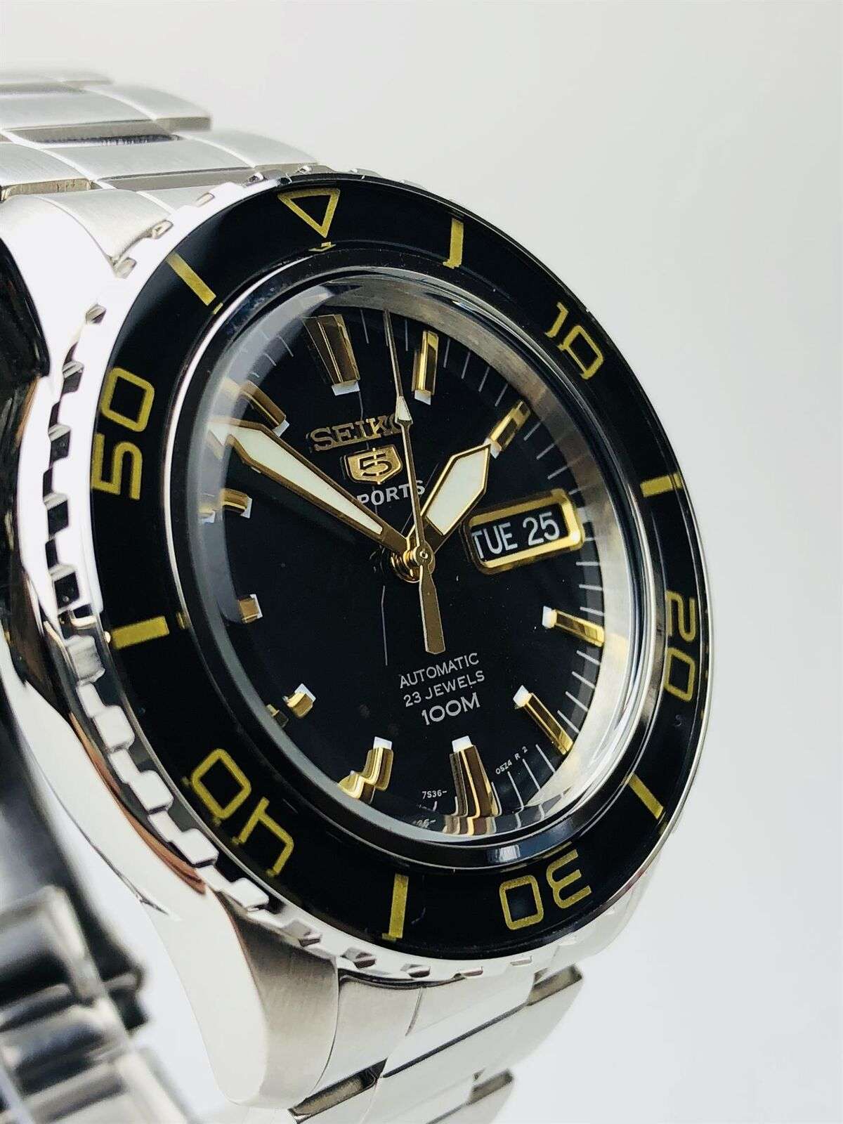 Men's stainless steel automatic watch close-up of black dial with gold markers and date