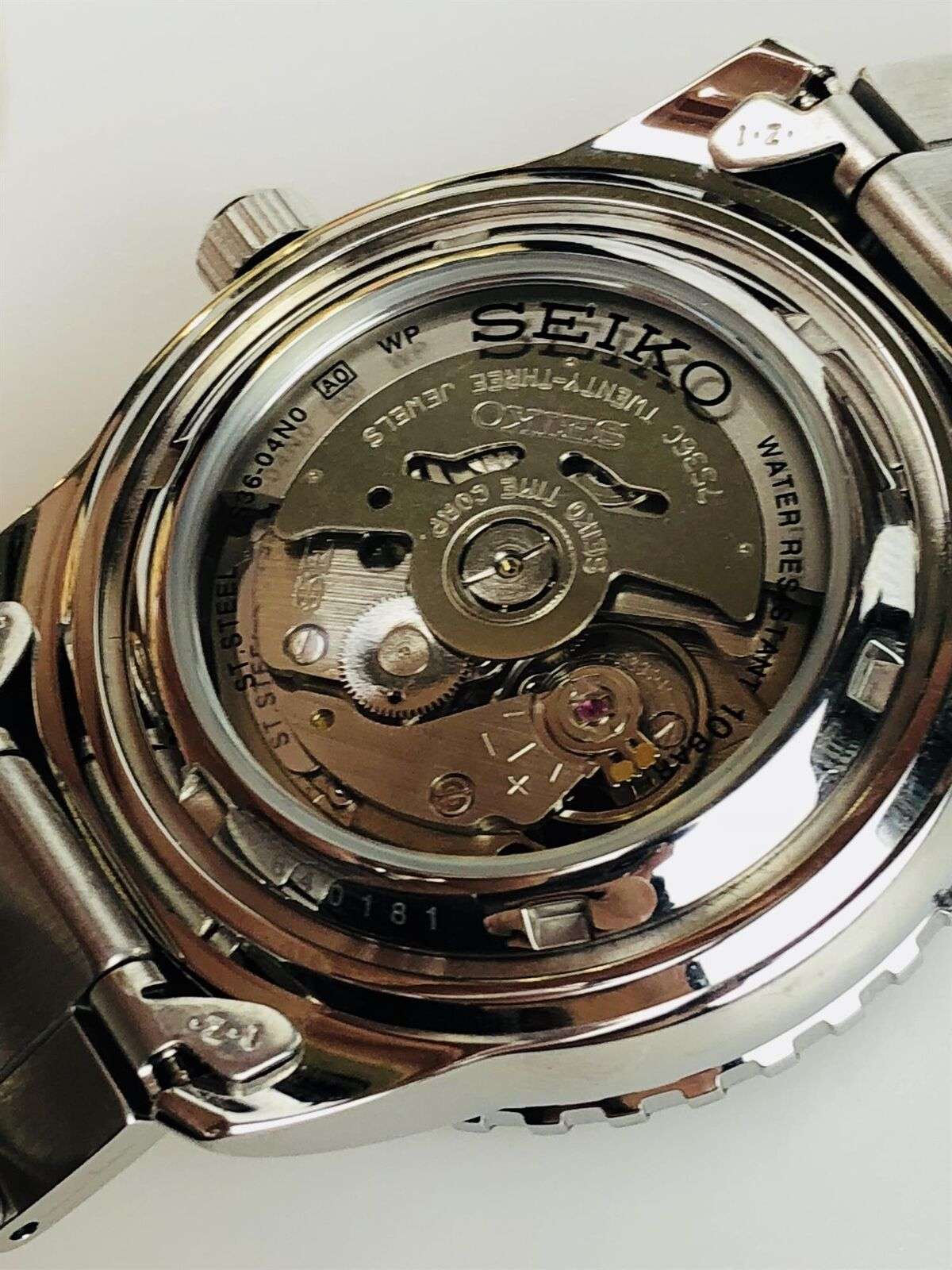 Men's stainless steel watch case back with visible mechanical movement and branding