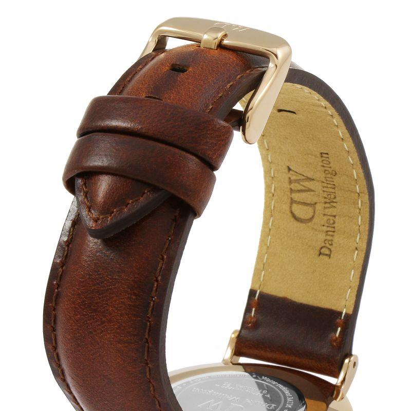 Brown leather watch strap with buckle and gold-tone case, underside view