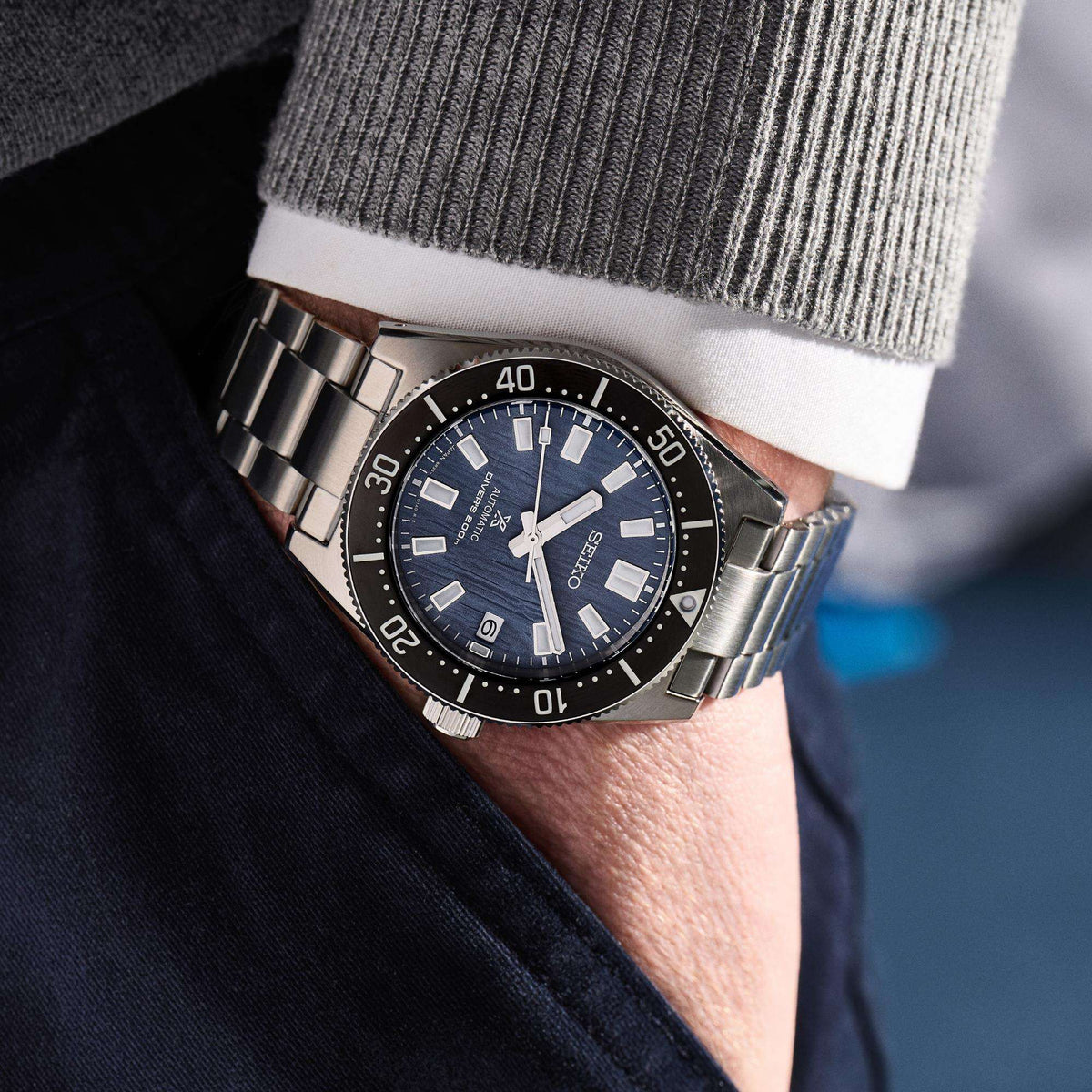 Close-up wrist shot of the Seiko Prospex Save The Ocean Glacier 1965 Mens Watch SPB297J1 being worn with a grey sweater and dark trousers.