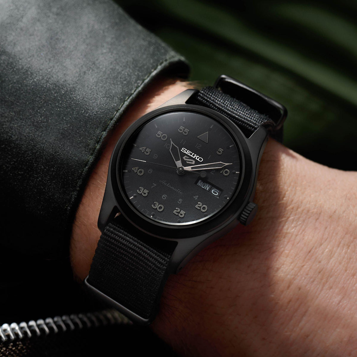 Men's black Seiko watch on black fabric strap, dark dial, MON 6