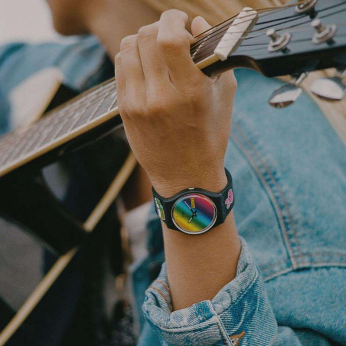 Black silicone quartz watch on wrist, multicolored rainbow dial with hands