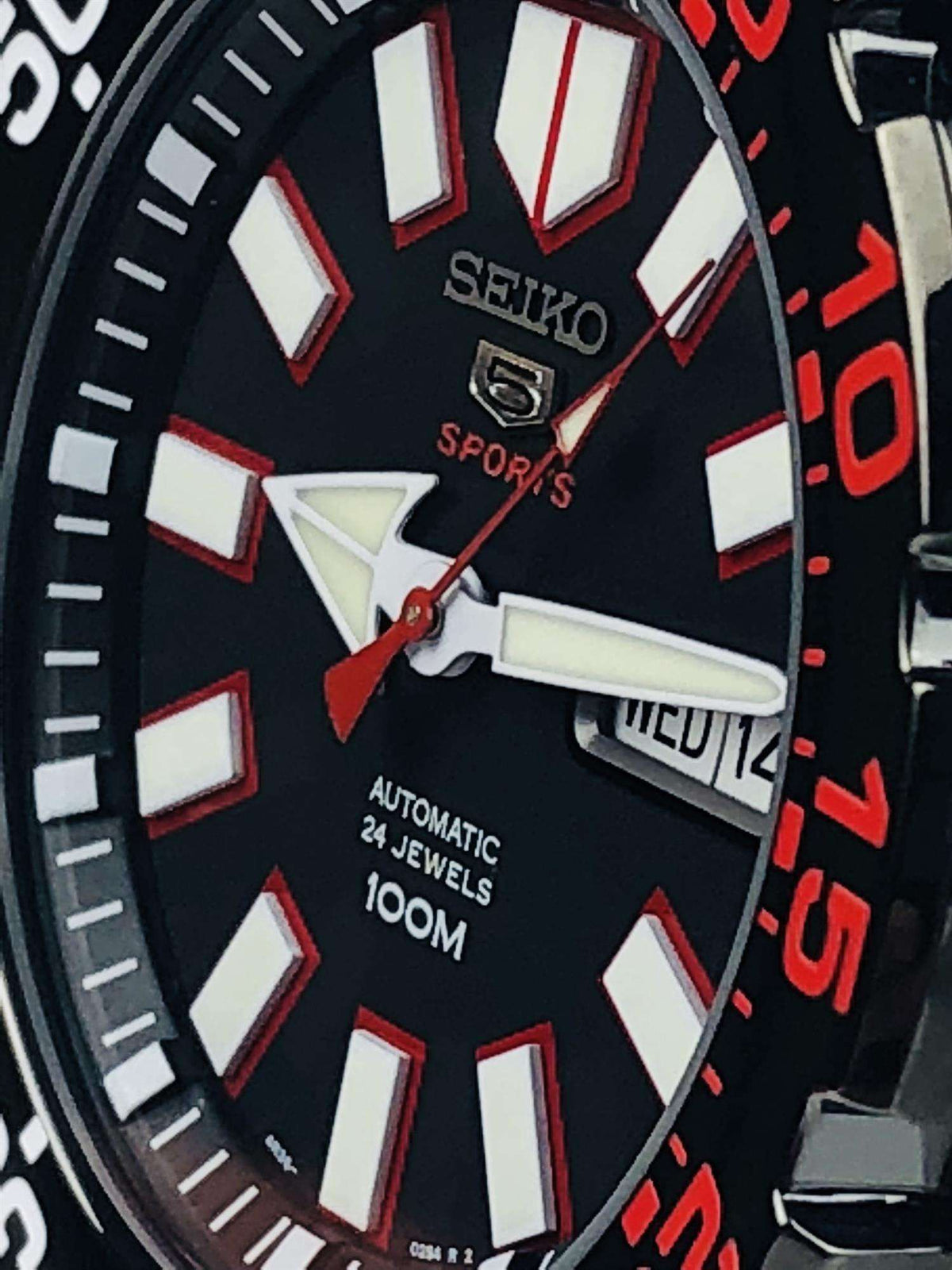 Seiko Sports automatic watch close-up: black dial, white/red markers, WED14 date