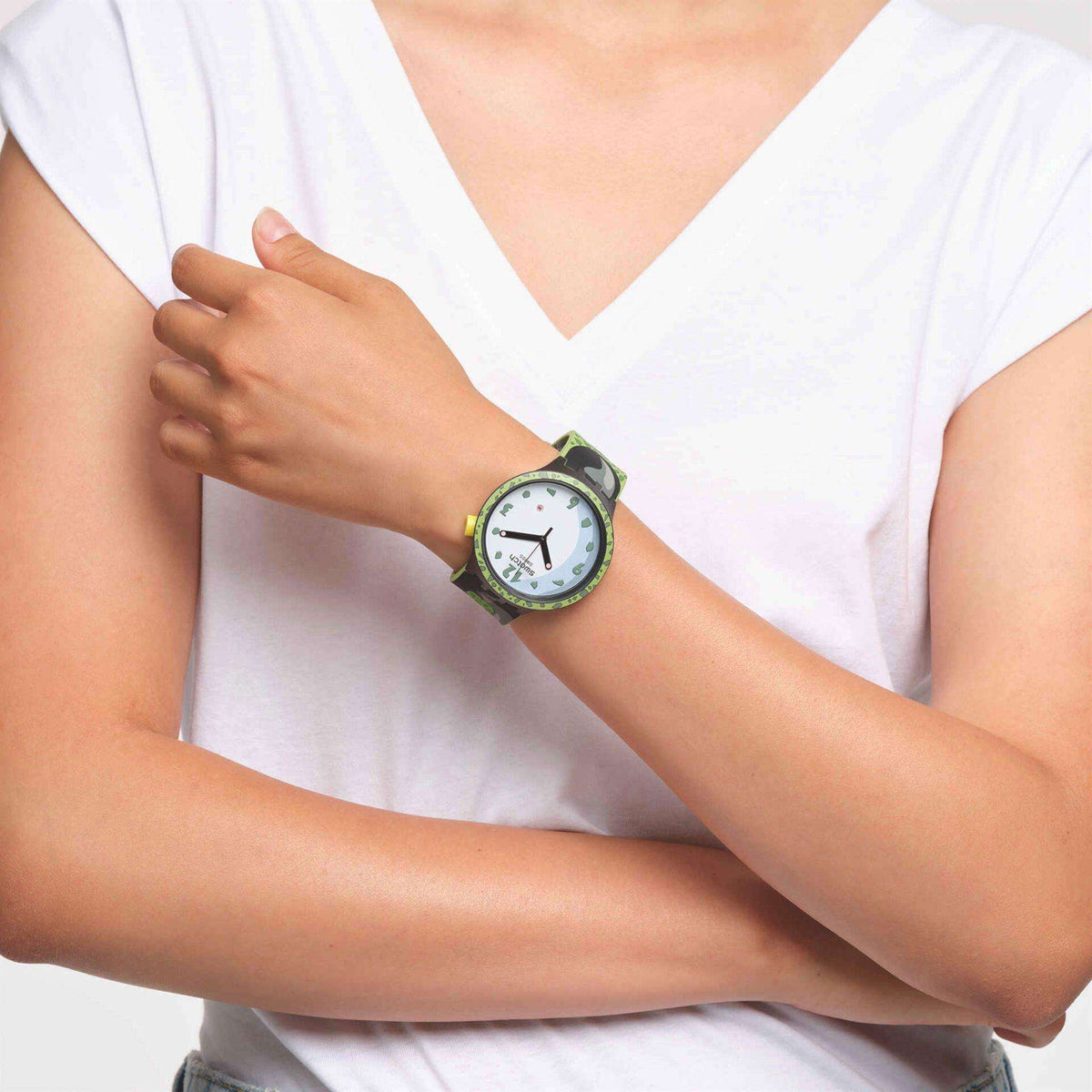 Quartz wristwatch on wrist with white dial, black bezel, and lime green silicone strap