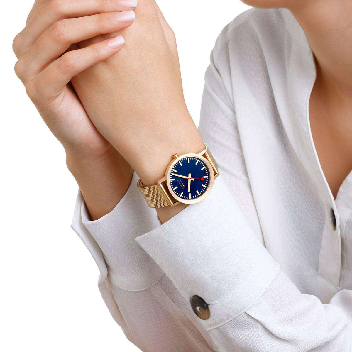 Gold mesh strap watch worn on wrist with dark blue dial and red seconds hand
