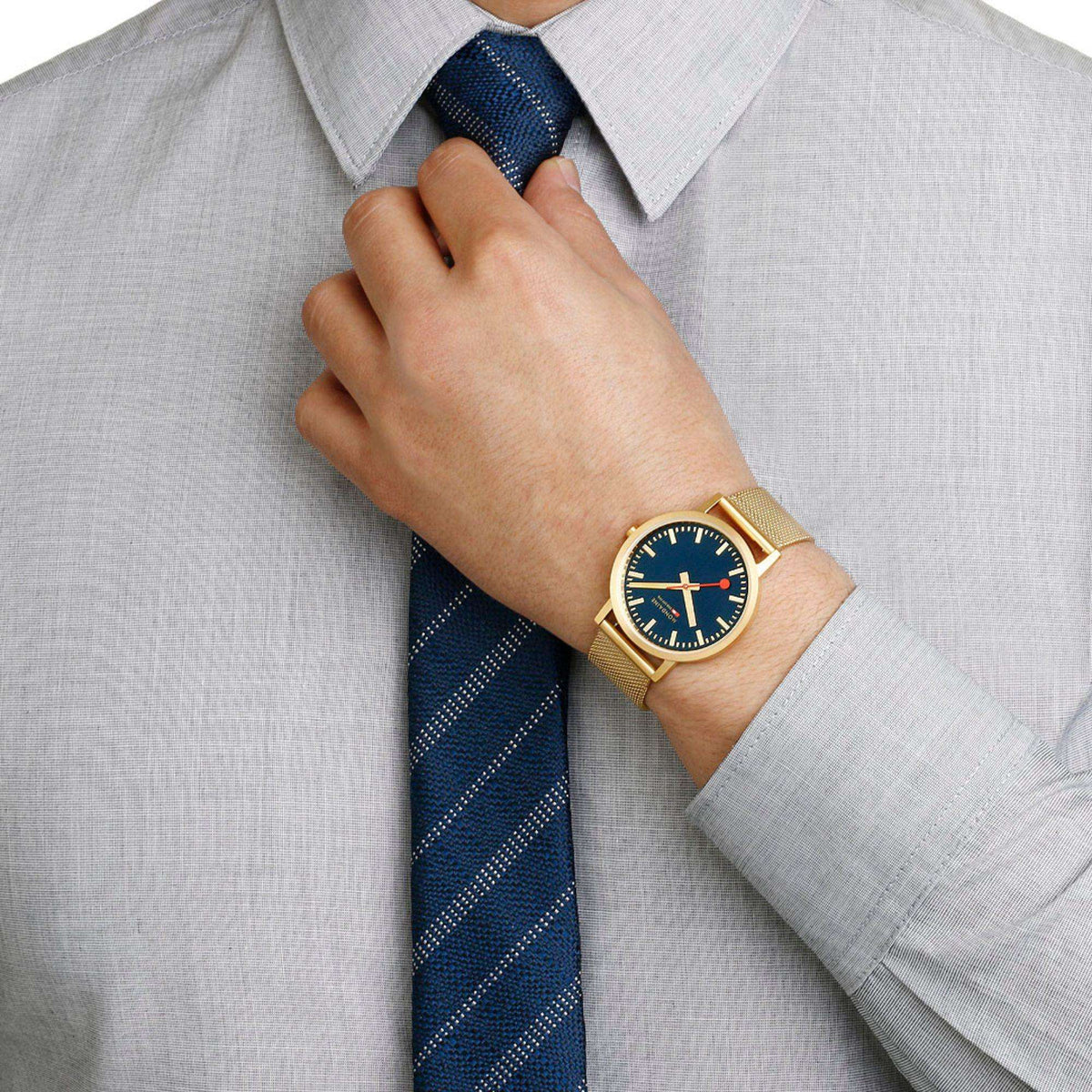 Gold mesh strap watch on wrist with dark blue dial and red seconds hand