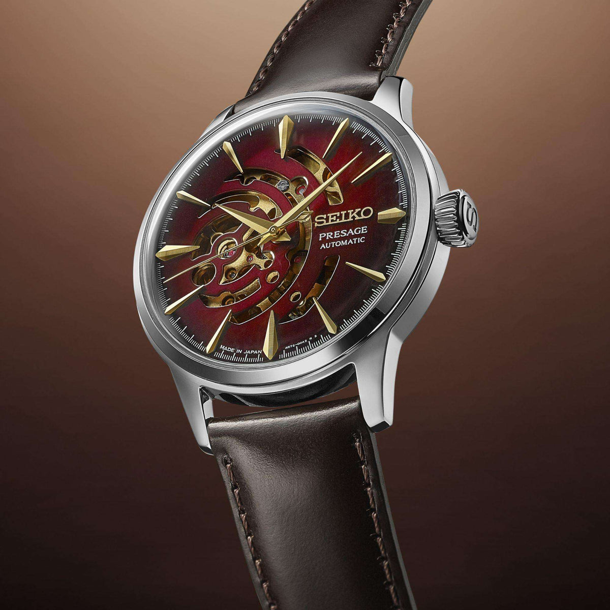 Men's automatic watch with red dial and gold-tone skeleton movement, black leather strap.