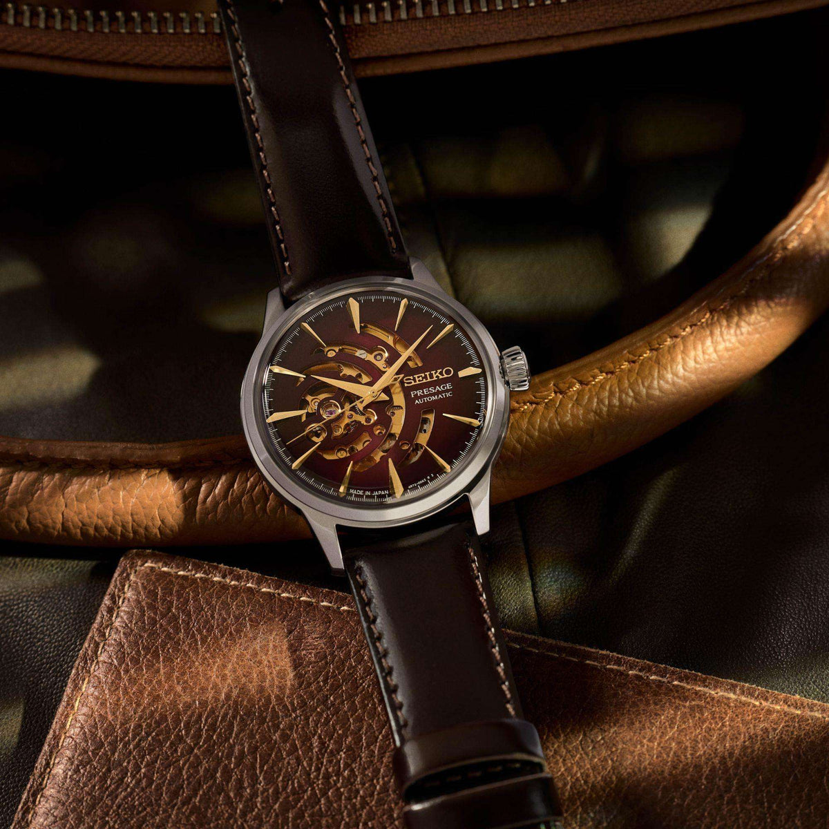Men's automatic watch on black leather strap with red dial and gold-tone skeleton movement.