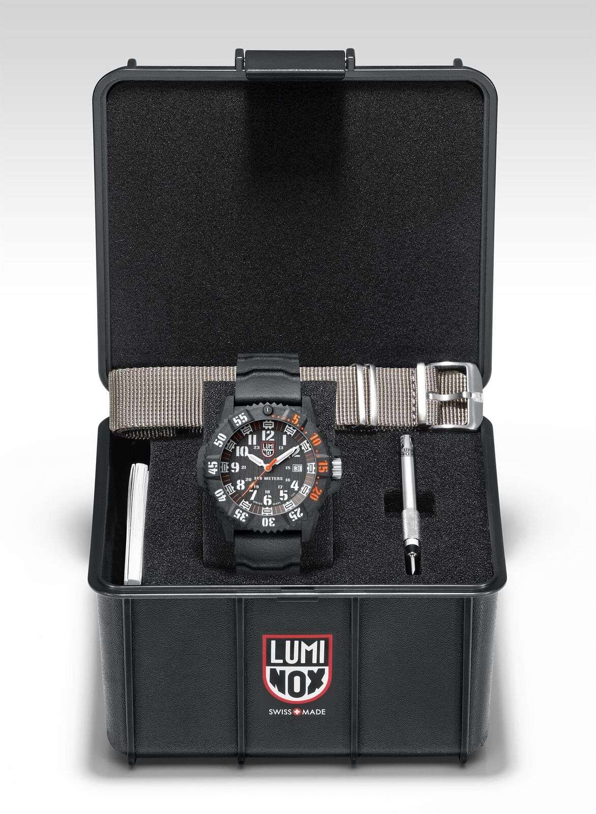 Watch with black dial and orange accents resting in a black storage box with strap hardware.