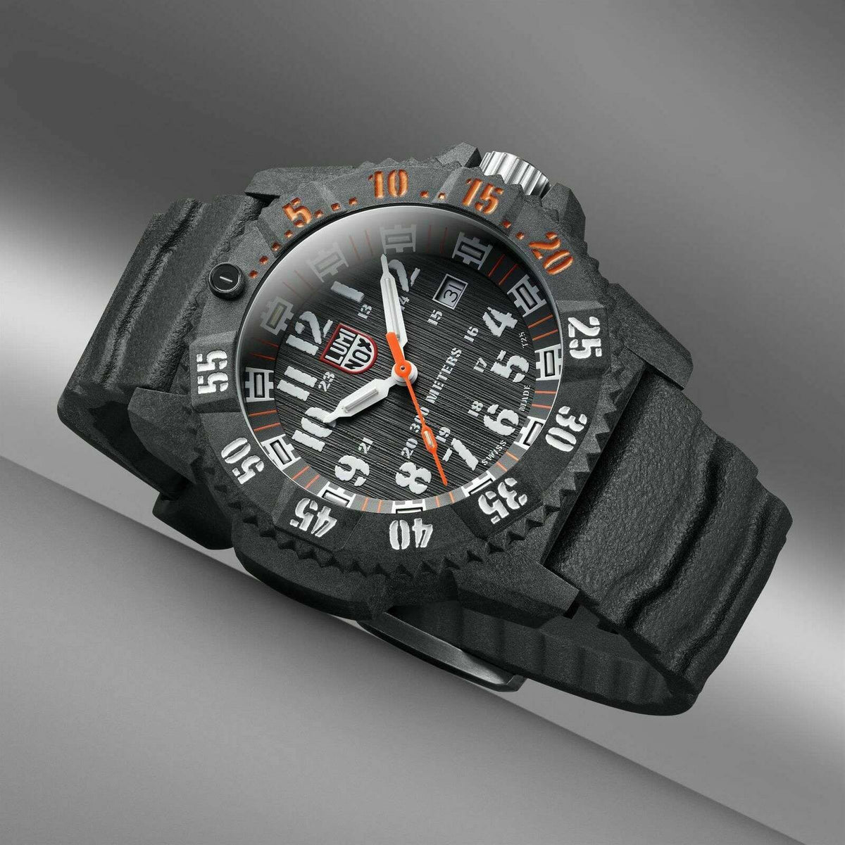 Angled carbon watch with black dial, orange minute markers, luminous hands, and rugged case details.