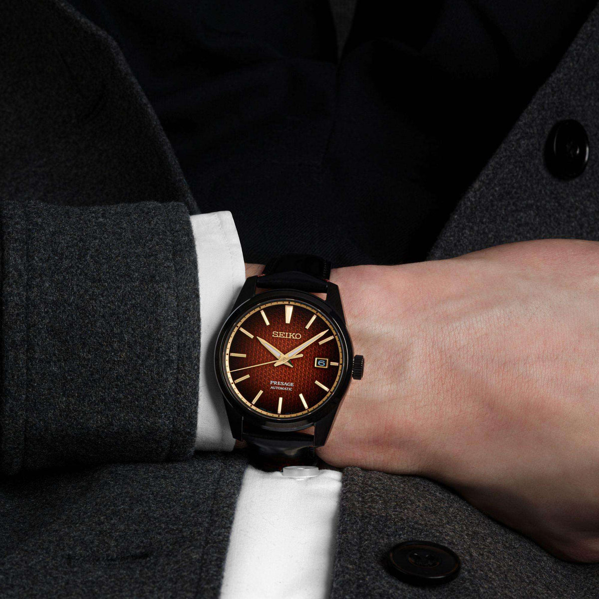 Seiko Presage men’s watch on wrist with red dial and black leather strap.