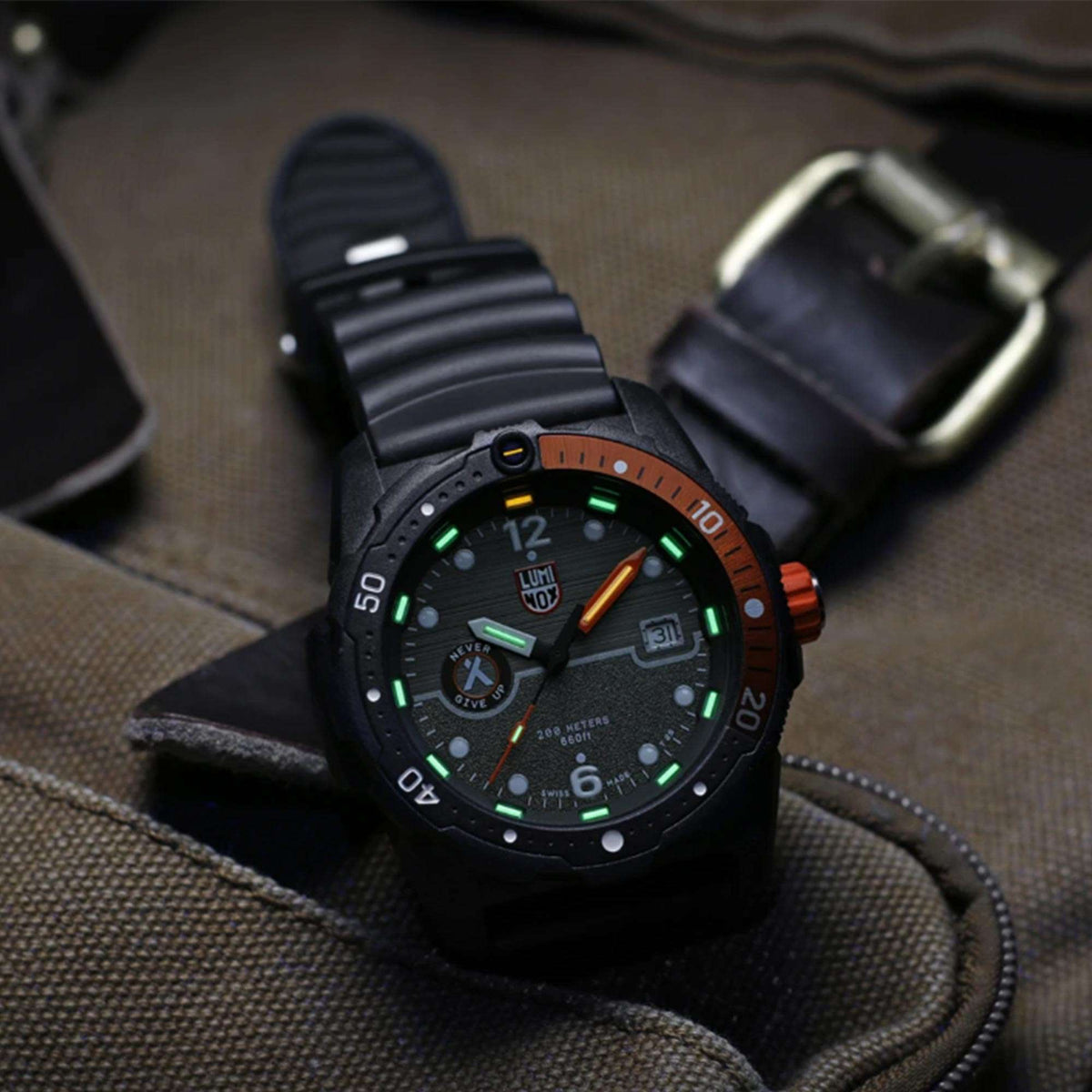 Black watch resting on fabric with green luminous dial and orange side crown guard