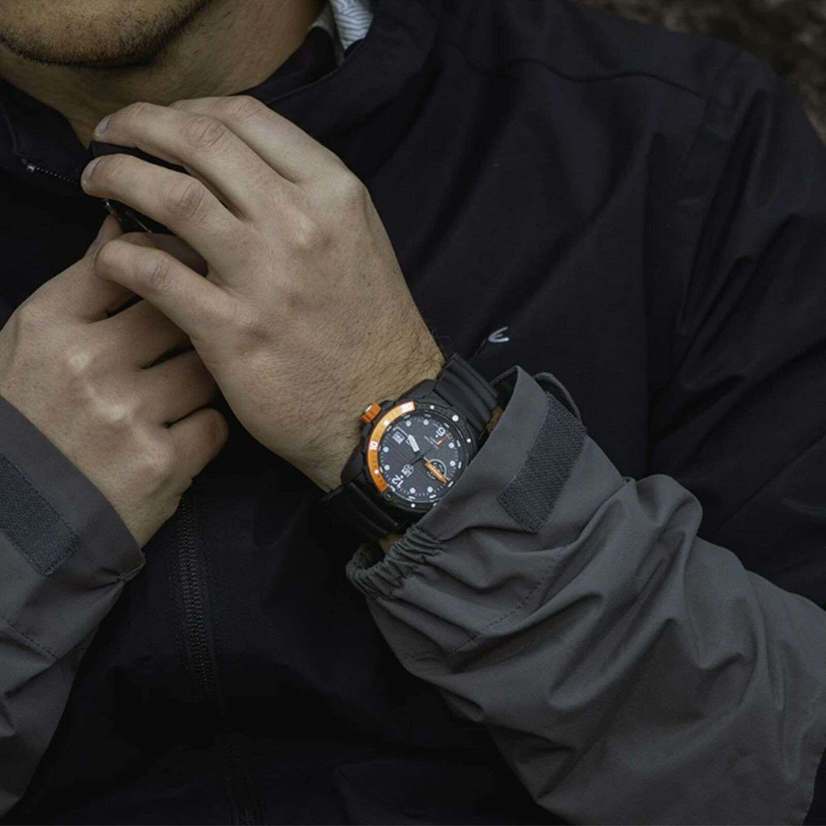 Men's black sports watch on wrist with dark dial and orange-accent bezel details