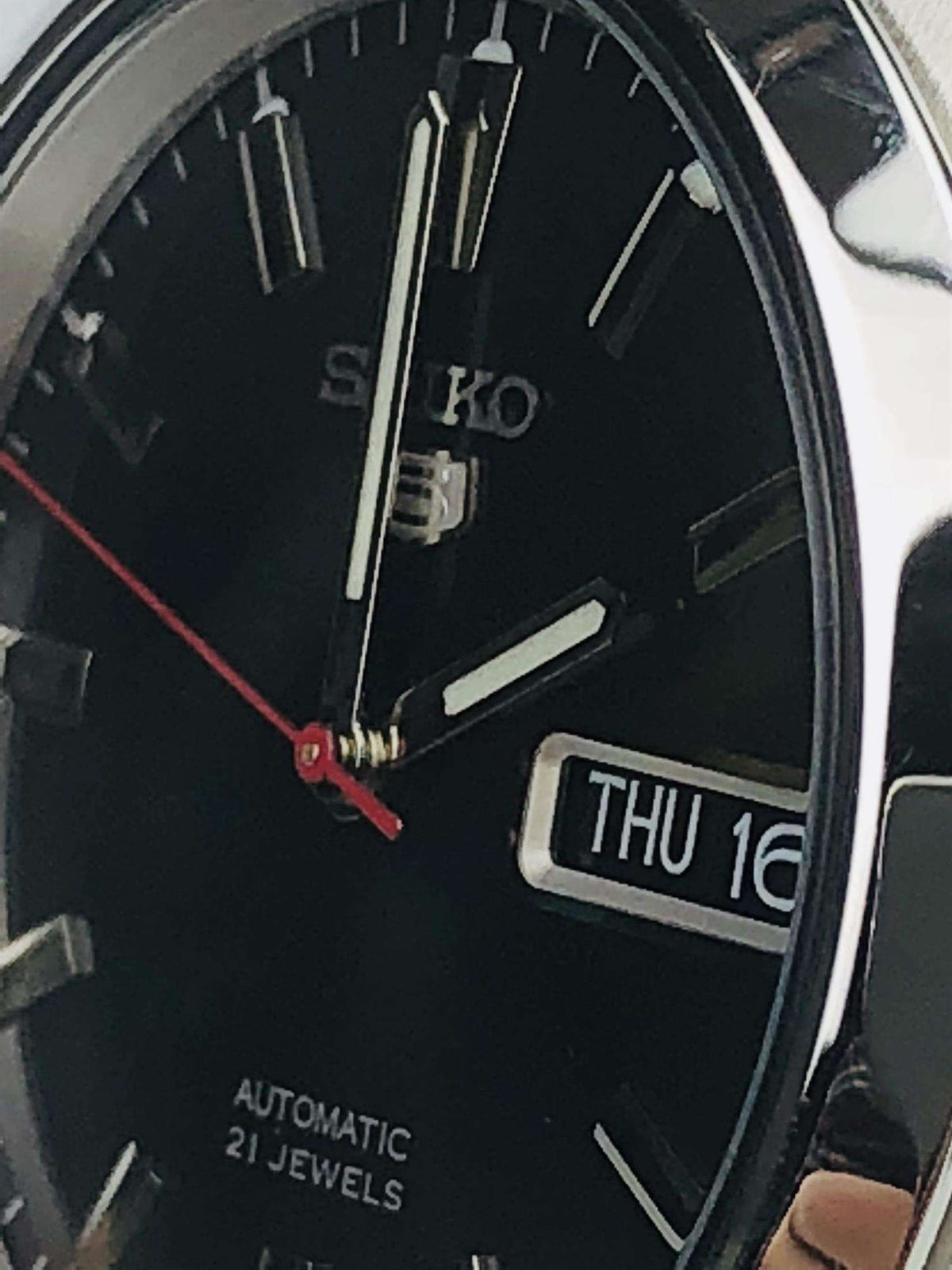 Men's black dial automatic watch with baton markers, red hands, and THU 16 date window.