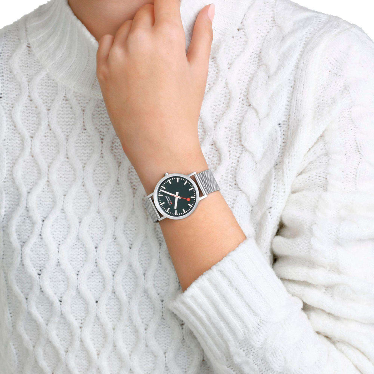 Wristwatch with forest green dial and silver mesh bracelet worn on arm