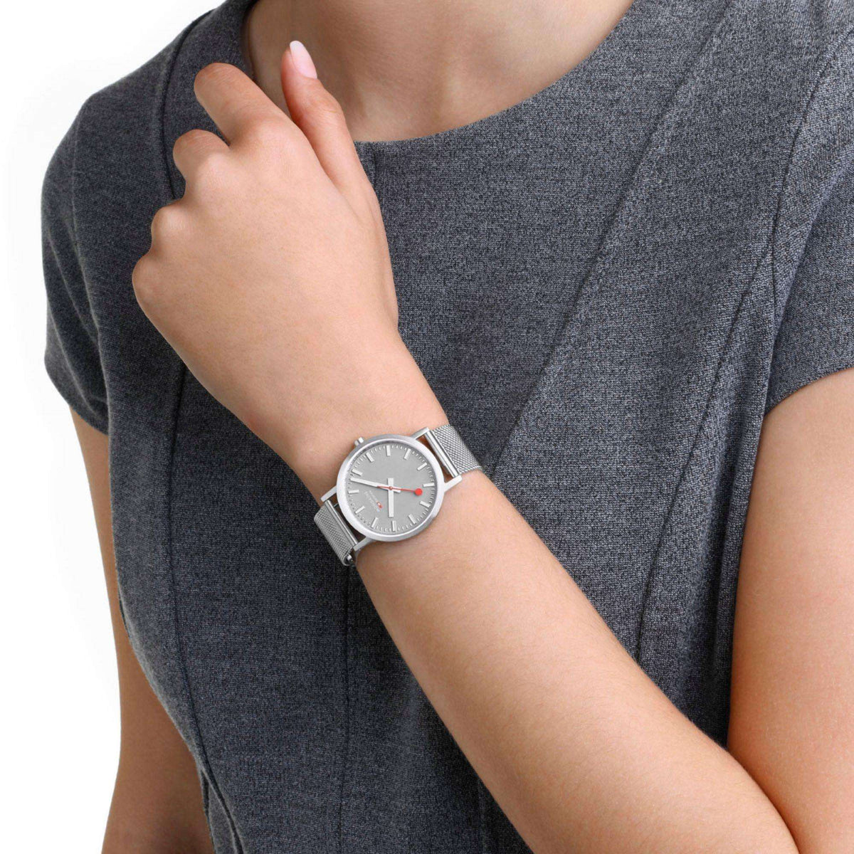 Stainless steel mesh bracelet watch with gray dial and red-accent hands on wrist