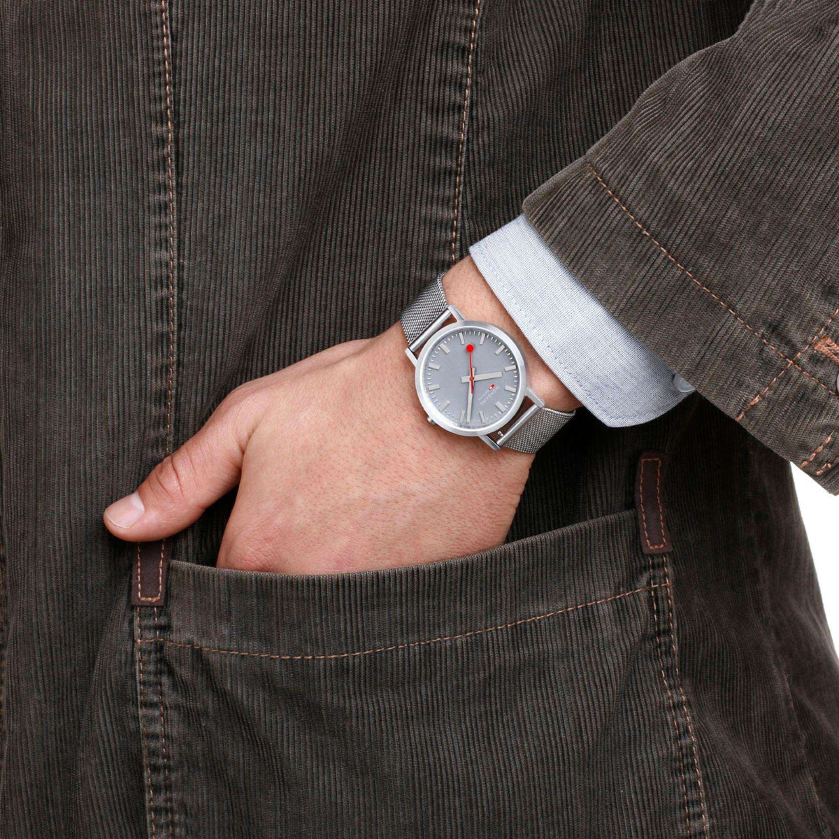 Stainless steel mesh bracelet watch with gray dial and red-accent hands on wrist
