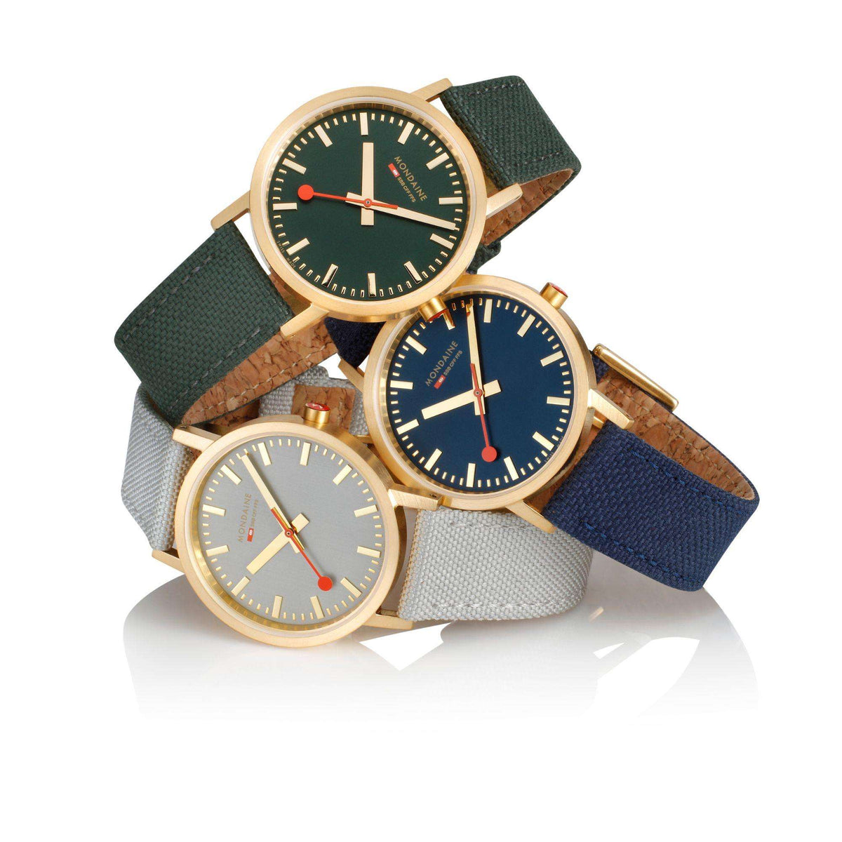 Mondaine gold-cased quartz watches shown together with textile straps in dark, navy, and gray